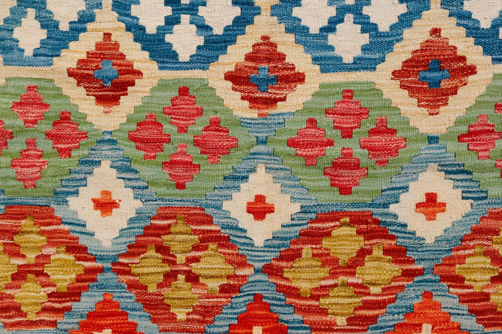 Handwoven Afghan Maimana kilim featuring a vibrant geometric pattern in red, blue, green, and cream.