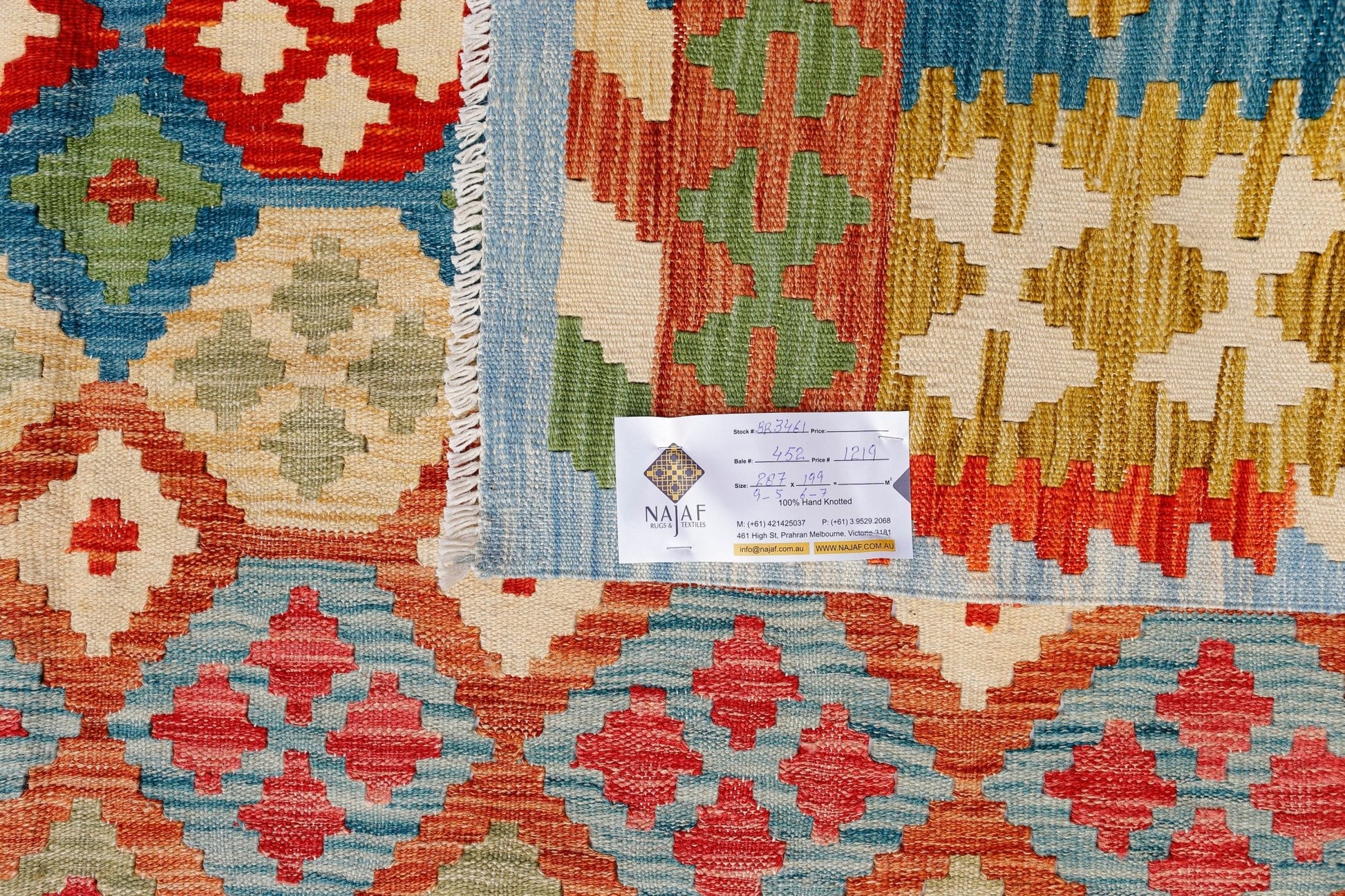 A handwoven Afghan Maimana kilim featuring a vibrant geometric pattern in red, blue, and gold.