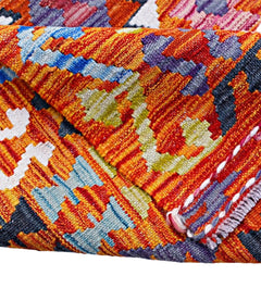 A folded Afghan Maimana kilim featuring a vibrant geometric pattern in wool.
