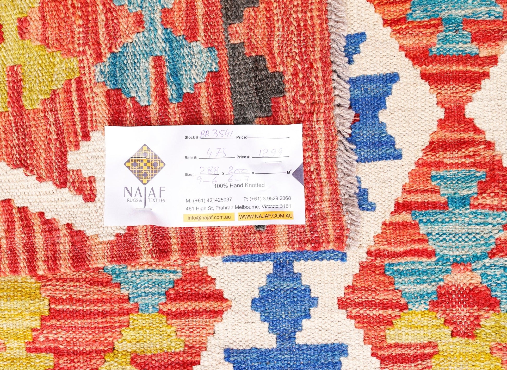 A handwoven Afghan Maimana kilim featuring a vibrant geometric pattern in red, blue, and yellow.