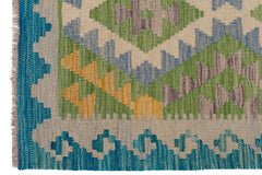 A handmade Afghan Maimana kilim featuring a geometric pattern in blue, green, and yellow wool.