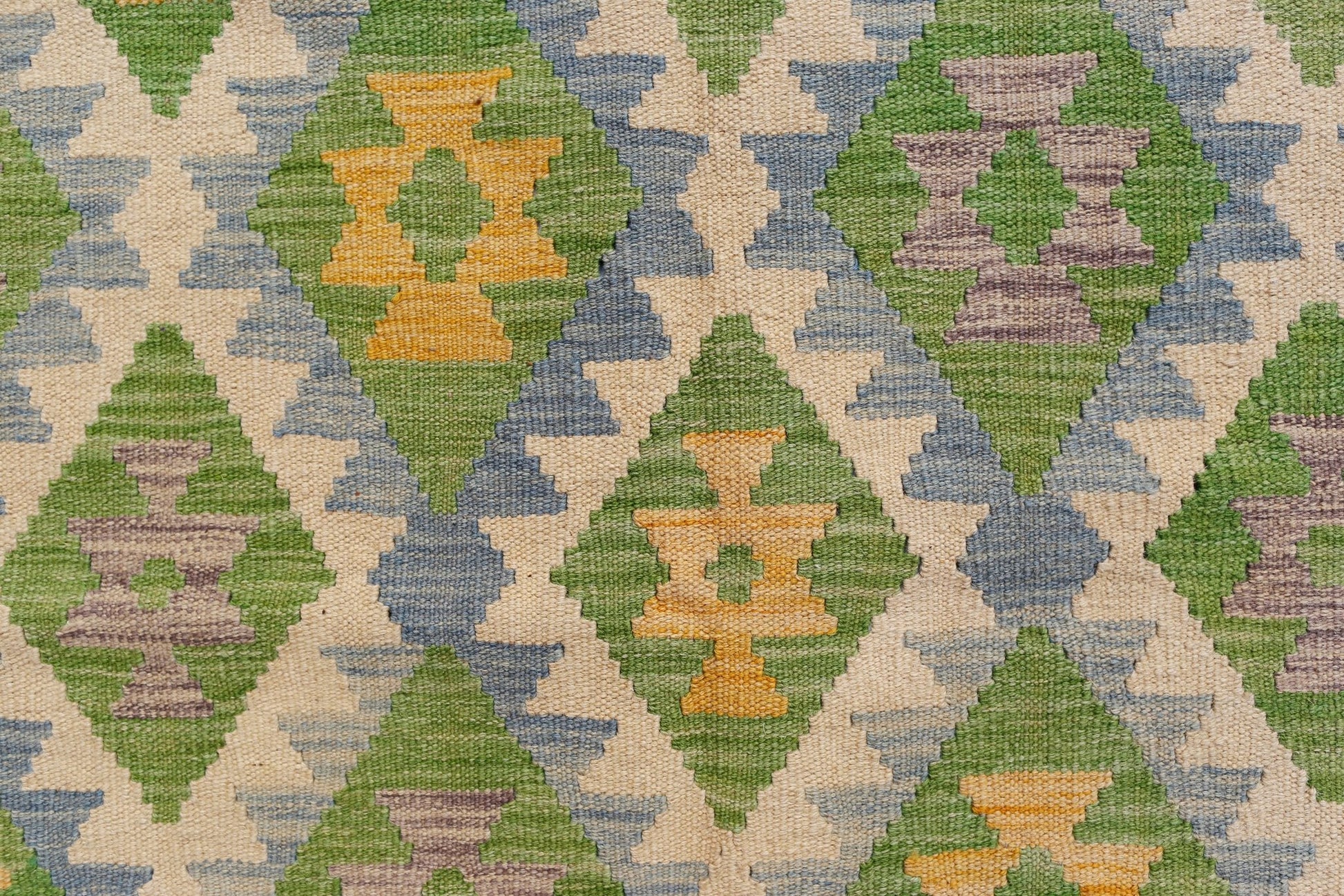 Handwoven Afghan Maimana kilim featuring a geometric diamond pattern in green, yellow, and purple.