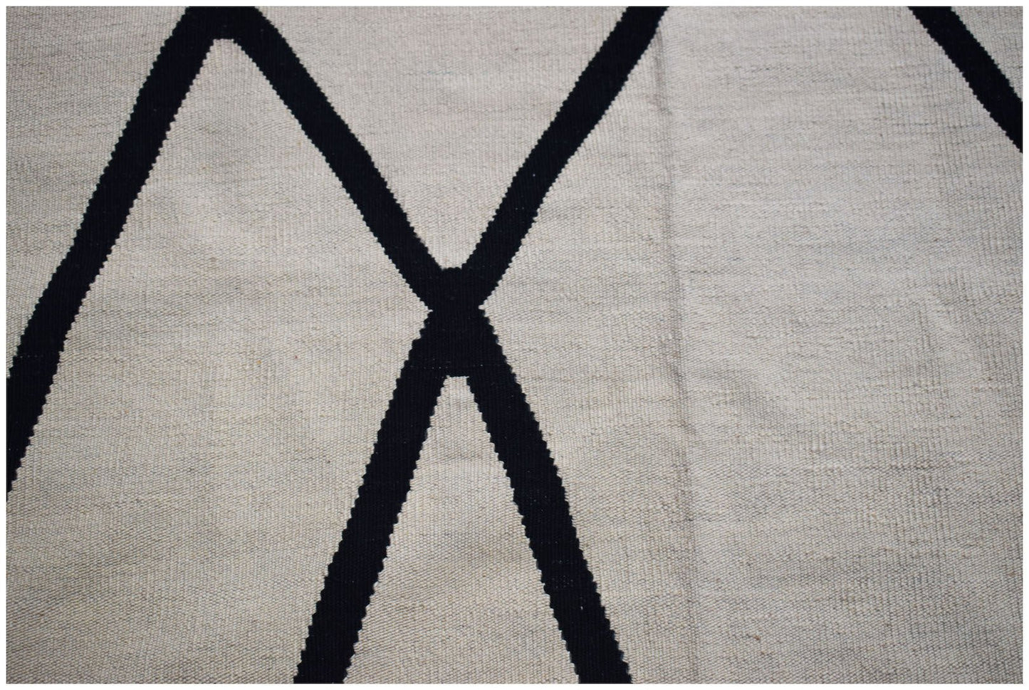 A handmade Afghan Maimana kilim featuring a minimalist black geometric pattern on a cream background.