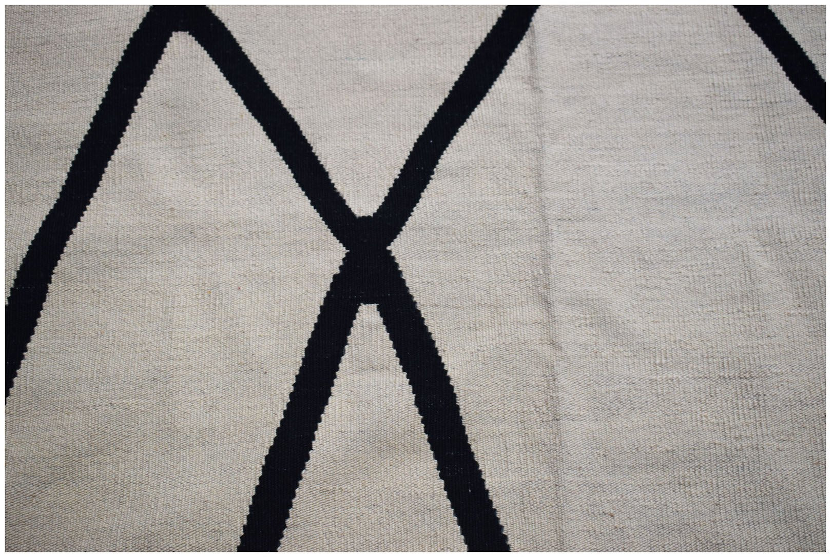 A handmade Afghan Maimana kilim featuring a minimalist black geometric pattern on a cream background.