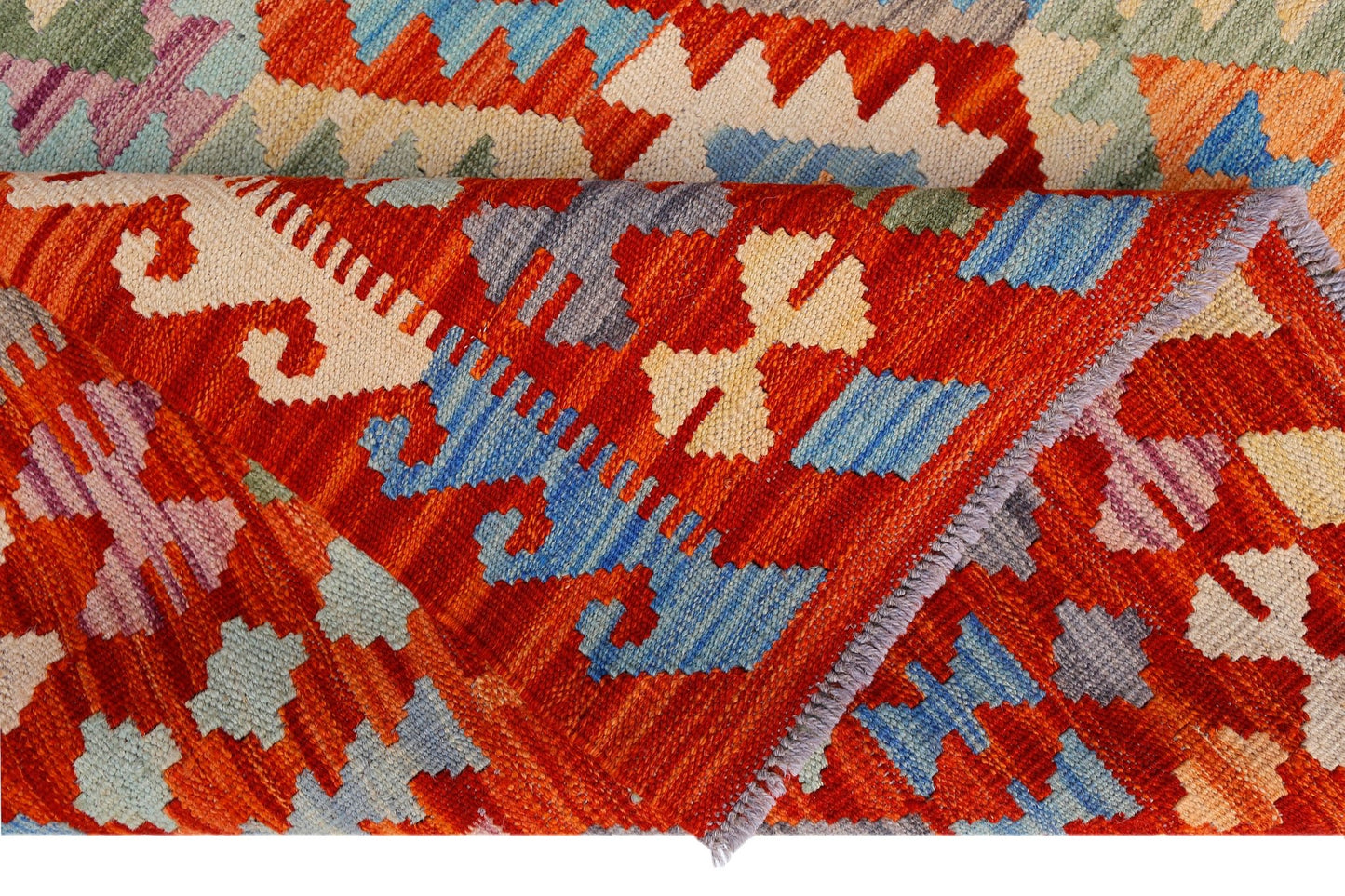 A handwoven Afghan Maimana kilim featuring a vibrant geometric pattern in red, blue, and cream.