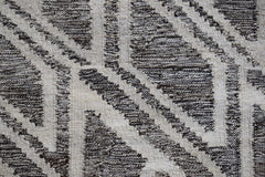 A handmade Afghan Maimana kilim rug featuring a geometric pattern in dark brown and cream wool.