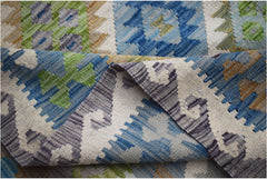 A handmade Afghan Maimana kilim rug featuring a geometric pattern in blue, green, and grey wool.