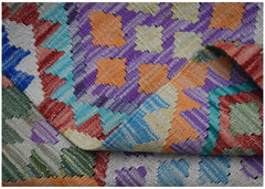 A handwoven Afghan Maimana kilim rug featuring a vibrant, geometric pattern in wool.