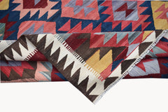 A handmade Afghan Maimana kilim rug featuring a geometric pattern in red, blue, and yellow wool.