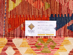 A handwoven Afghan Maimana kilim featuring a geometric pattern in warm red, yellow, and blue tones.