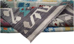 A folded Afghan Maimana kilim rug featuring a geometric pattern in grey, blue, and red wool.