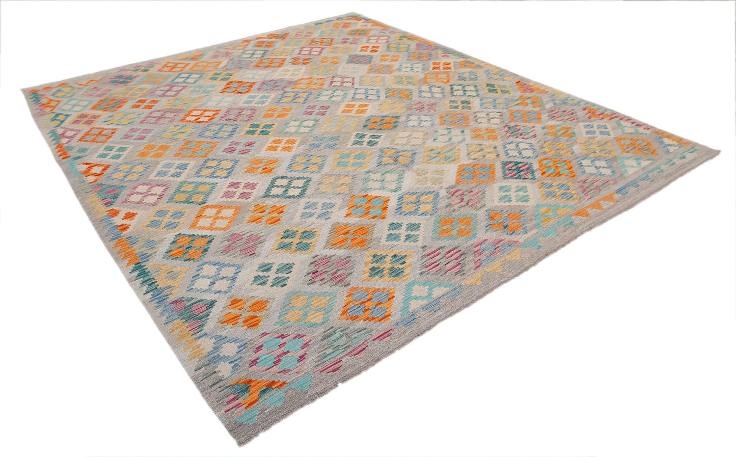 Handwoven Afghan Maimana kilim rug featuring a colorful geometric pattern on a light grey background.
