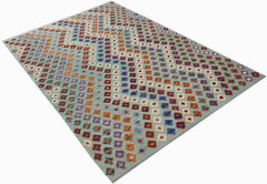A handmade Afghan Maimana kilim rug featuring a light blue background with colorful geometric motifs.