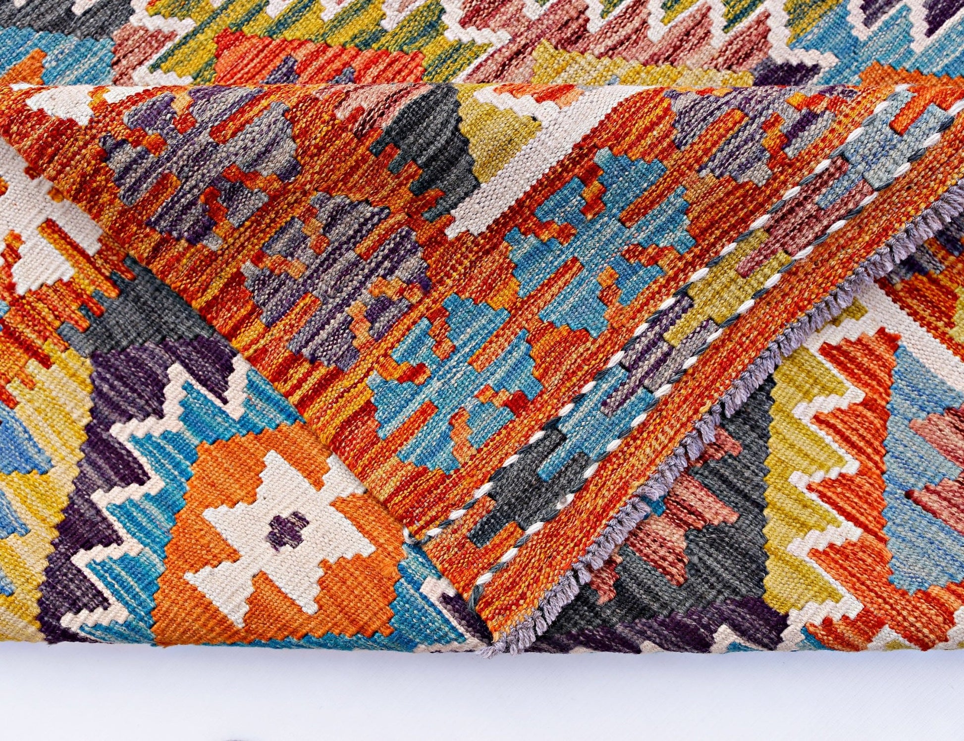 A handwoven Afghan Maimana kilim featuring a vibrant geometric pattern in wool.