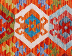 A handwoven Afghan Maimana kilim featuring a vibrant geometric pattern in wool.