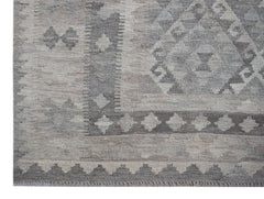 A handwoven Afghan Maiamana kilim rug featuring a grey and beige geometric pattern.