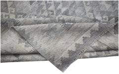 A handwoven Afghan Maimana kilim rug featuring a grey and beige geometric pattern.