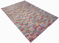 A handmade Afghan Maimana kilim rug featuring a repeating pattern of colorful floral motifs.