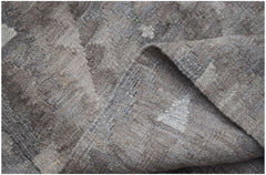 A handwoven Afghan Maimana kilim rug featuring a neutral geometric pattern in undyed wool.