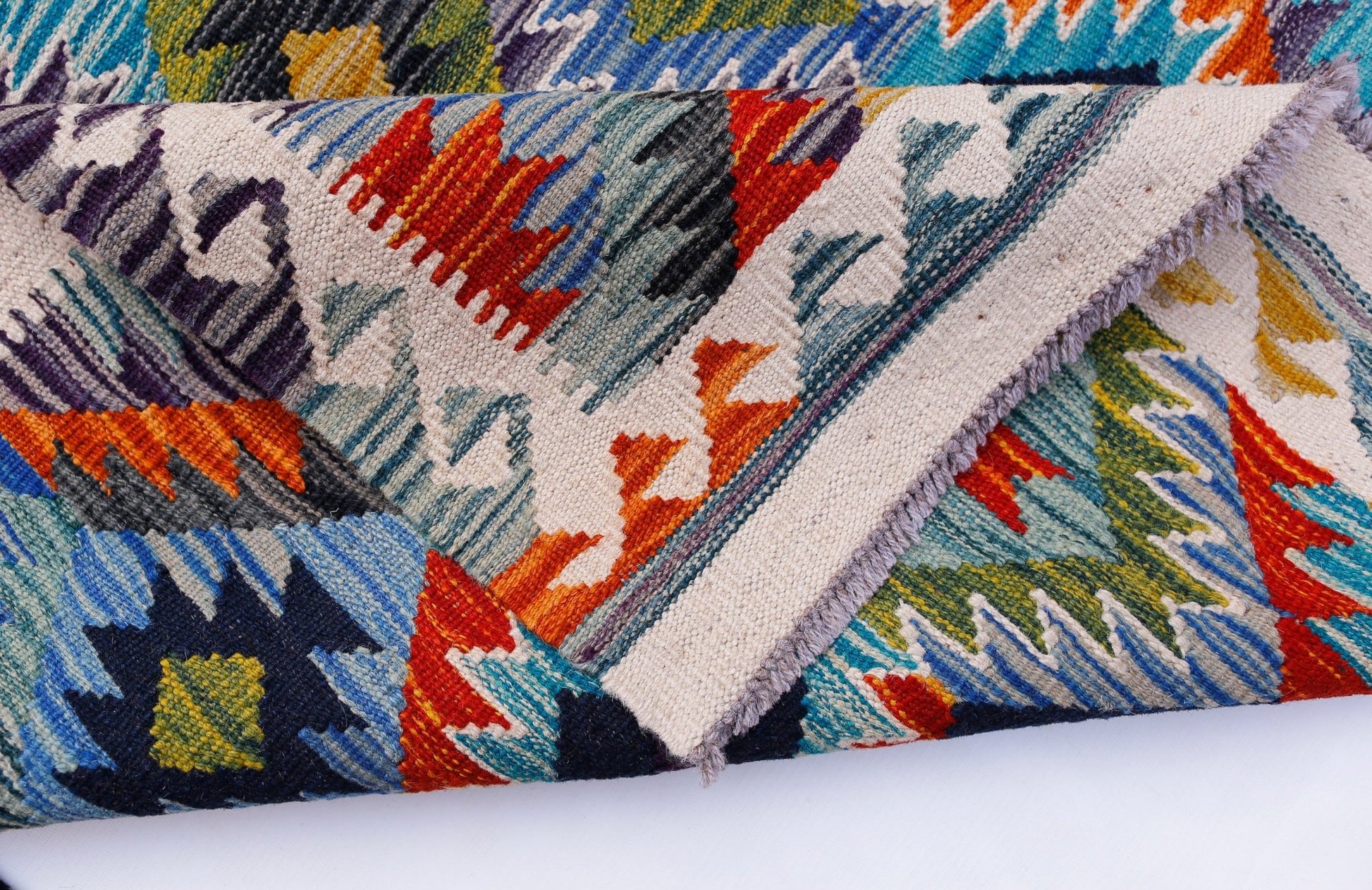 A handwoven Afghan Maimana kilim rug featuring vibrant geometric patterns in wool.