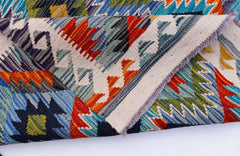 A handwoven Afghan Maimana kilim rug featuring vibrant geometric patterns in wool.