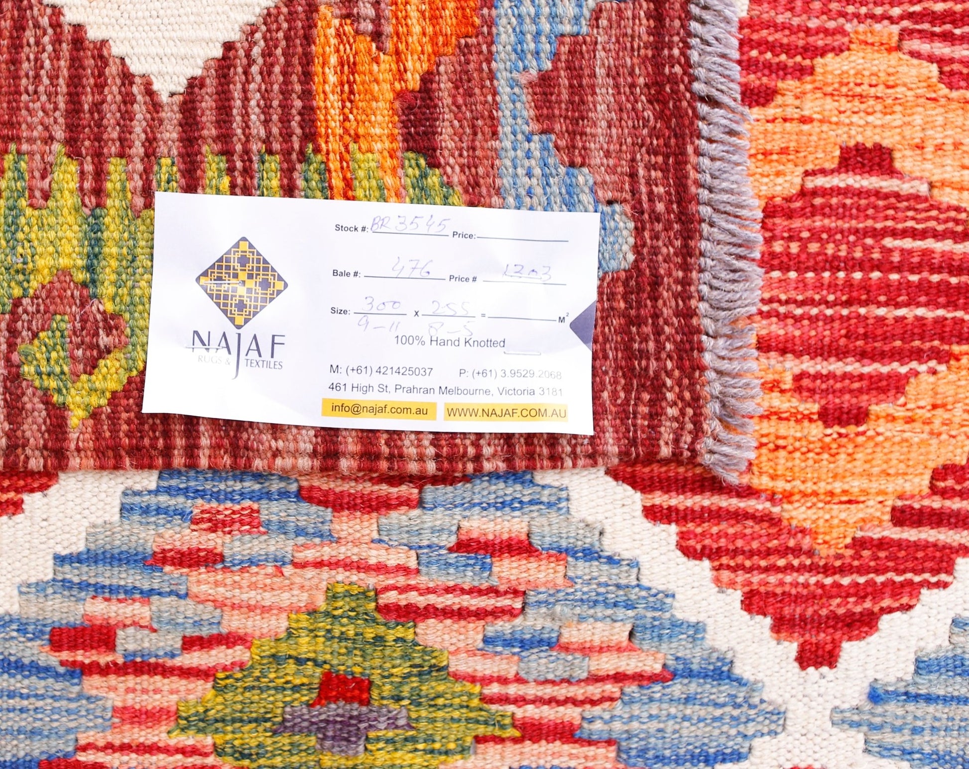 A handwoven Afghan Maimana kilim featuring a vibrant geometric pattern in red, orange, and blue.