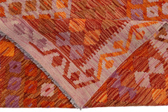 A handmade Afghan Maimana kilim rug featuring a geometric pattern in shades of orange and purple.