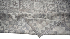 A handwoven Afghan Maimana kilim rug featuring a geometric pattern in shades of grey and white.