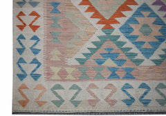Handwoven Afghan Maimana kilim featuring a geometric pattern in soft orange, blue, and pink tones.