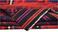 A folded Afghan Maimana kilim featuring geometric patterns in red, blue, and black wool.