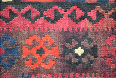 A close-up of a handmade Afghan Maimana kilim featuring geometric patterns in red, blue, and black.
