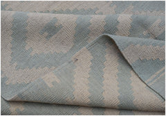 A handwoven Afghan Maimana kilim rug featuring a geometric pattern in light blue and cream wool.
