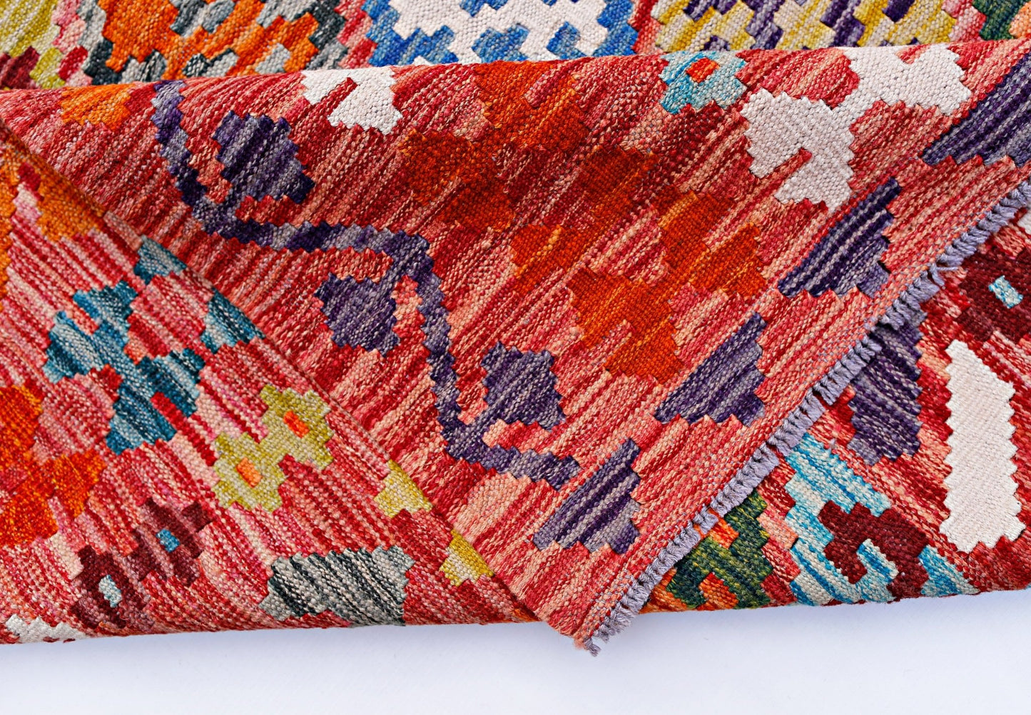 A handwoven Afghan Maimana kilim rug featuring a vibrant geometric pattern in red and multi-colors.