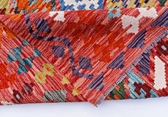 A handwoven Afghan Maimana kilim rug featuring a vibrant geometric pattern in red and multi-colors.