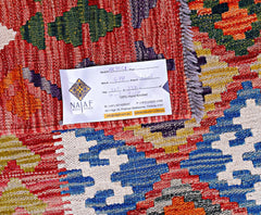 A handwoven Afghan Maimana kilim featuring a vibrant geometric pattern in red, blue, and yellow.