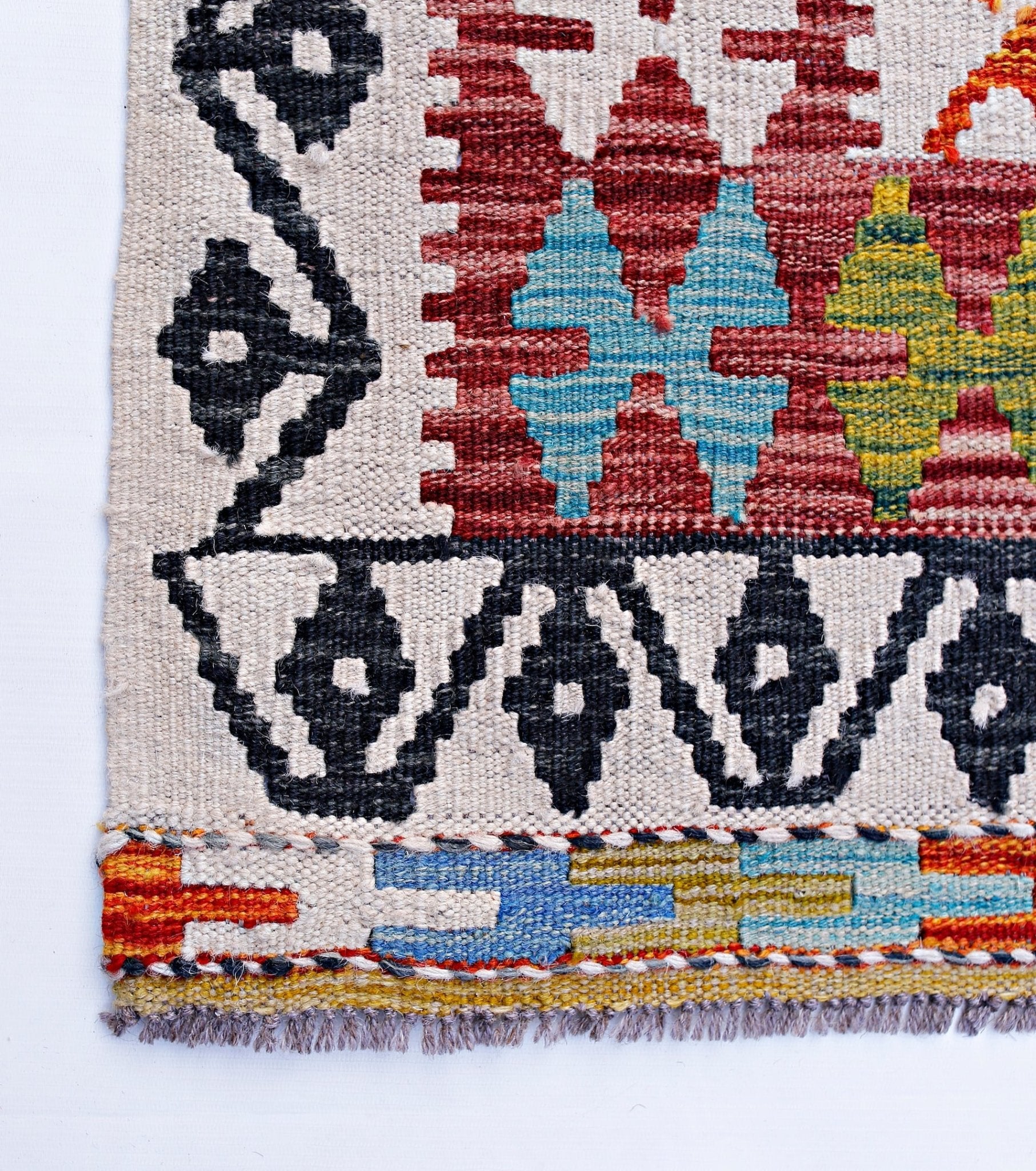 Handwoven Afghan Maimana kilim featuring geometric patterns in red, blue, yellow, and black wool.