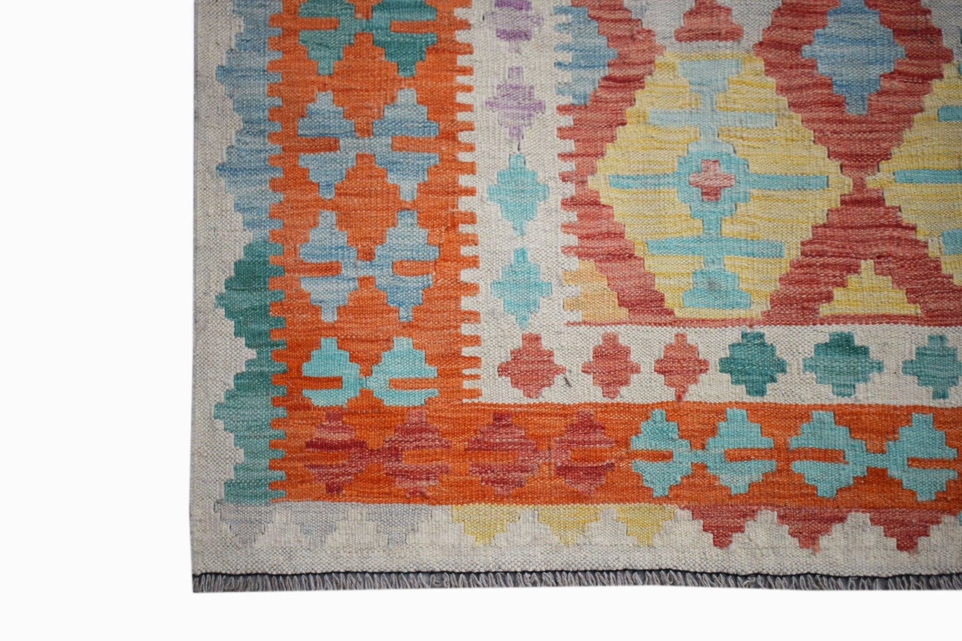 A handmade Afghan Maimana kilim rug featuring a geometric pattern in vibrant orange, blue, and red.