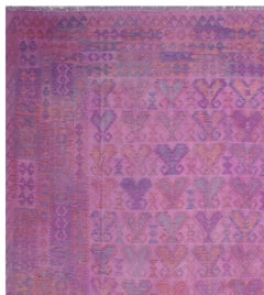 A handmade Afghan Maiamana kilim rug featuring a geometric pattern in shades of purple and pink.