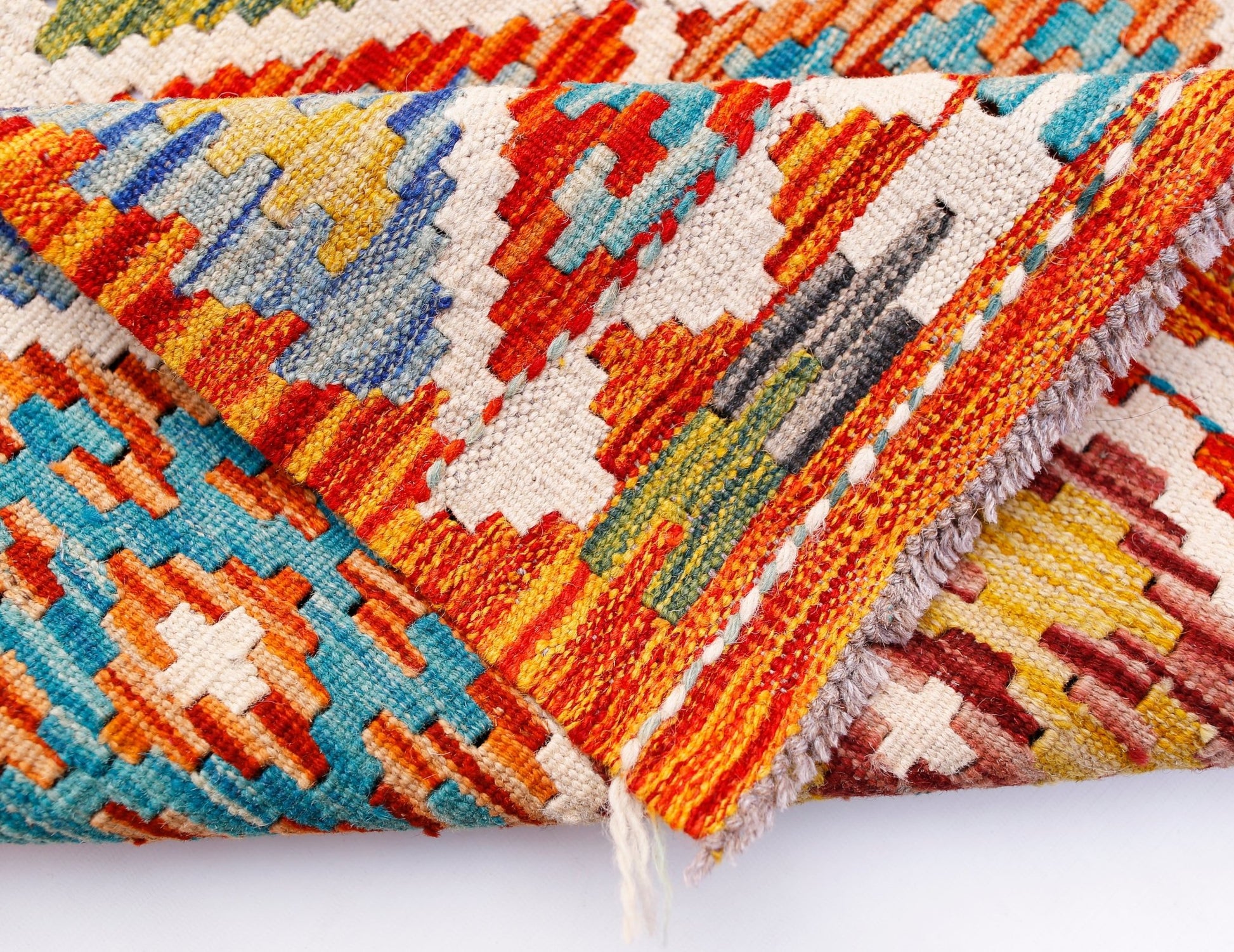 A folded Afghan Maimana Kilim runner featuring vibrant geometric patterns in wool.