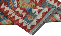 A handwoven Afghan Maimana wool kilim runner featuring a geometric pattern in red, blue, and green.