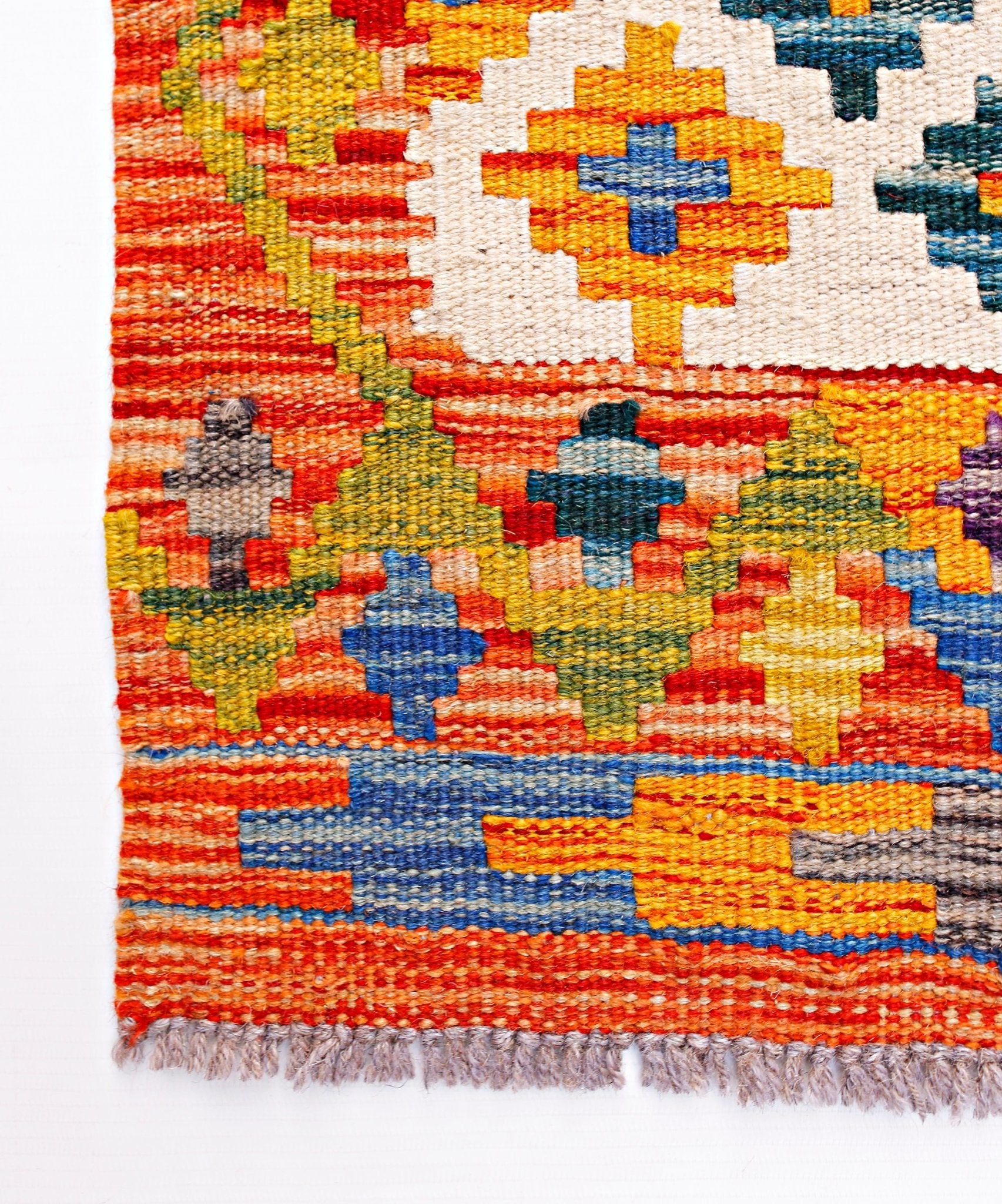 Handwoven Afghan Maimana wool runner featuring a vibrant geometric pattern and fringed edges.