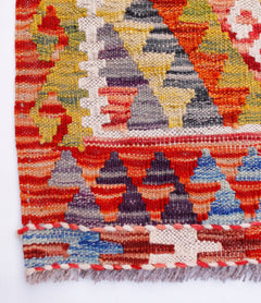 A handmade Afghan Maimana kilim runner featuring a vibrant geometric pattern in wool.