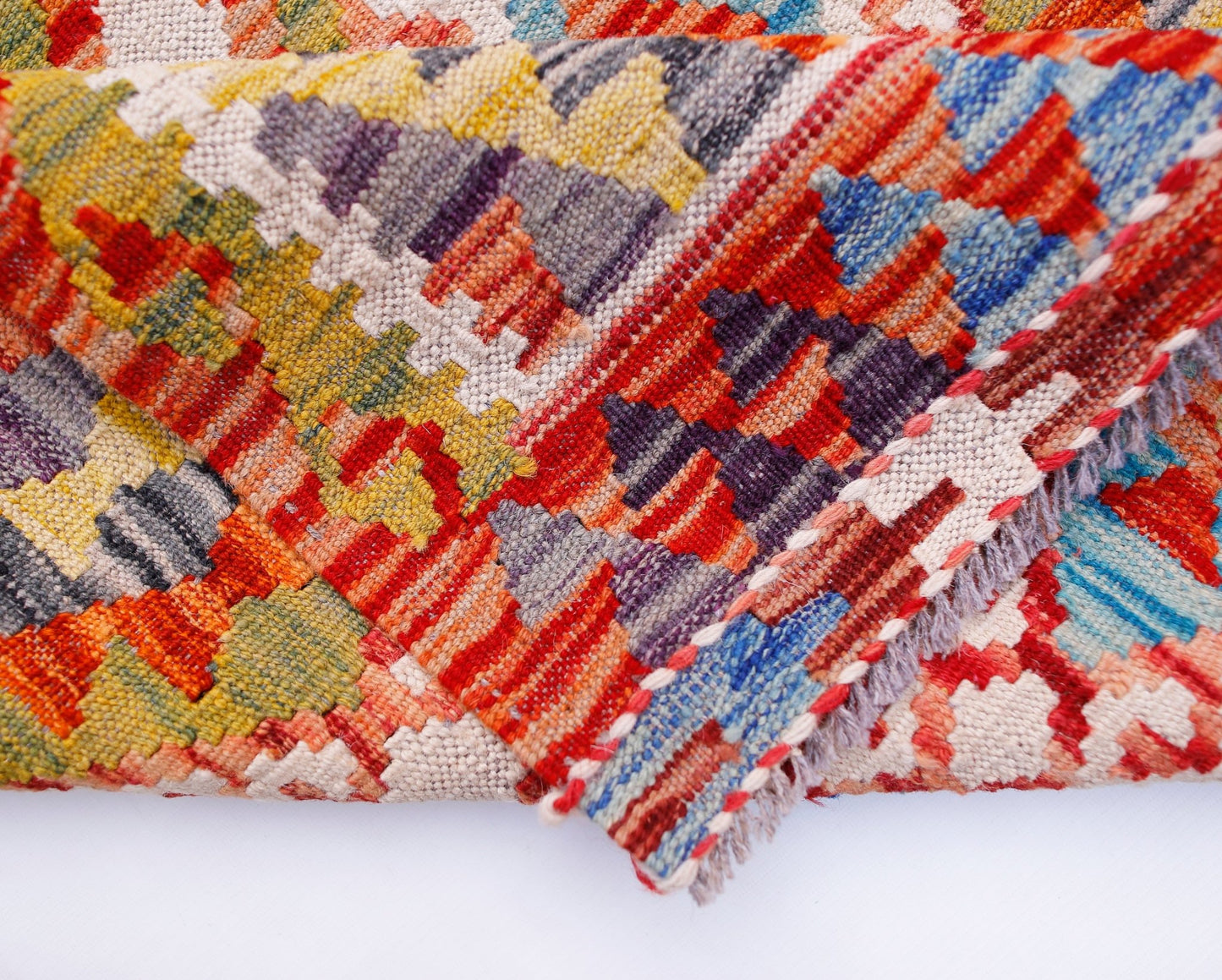 A handwoven Afghan Maimana kilim runner featuring a vibrant geometric pattern in wool.