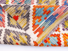 A folded Afghan Maimana kilim runner featuring a vibrant geometric pattern in wool.