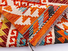 A folded Afghan Maimana kilim runner featuring vibrant geometric patterns in wool.