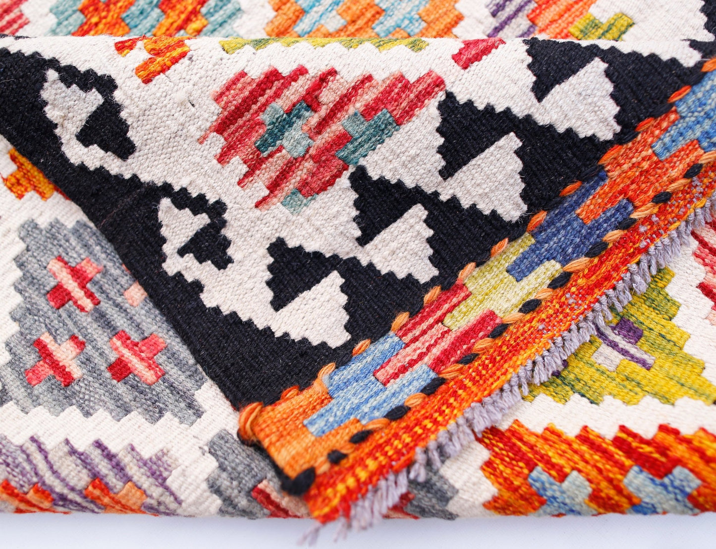 A handwoven Afghan Maimana wool kilim runner featuring a vibrant geometric pattern.