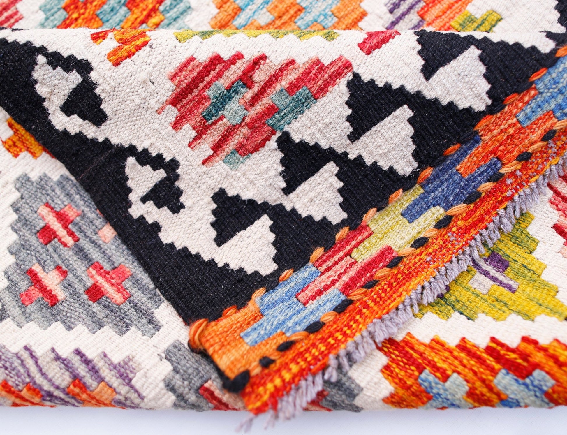 A handwoven Afghan Maimana wool kilim runner featuring a vibrant geometric pattern.