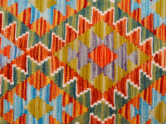 A handmade Afghan Maimana kilim runner featuring a vibrant geometric pattern in wool.