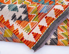 A handwoven Afghan Maimana wool kilim runner featuring a vibrant geometric pattern.