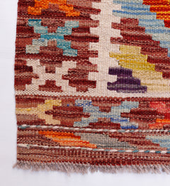 Handwoven Afghan Maimana wool runner featuring a colorful geometric pattern and fringed edges.